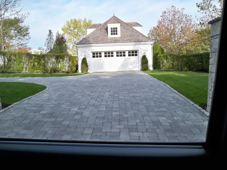 Paver driveway leading to a garage