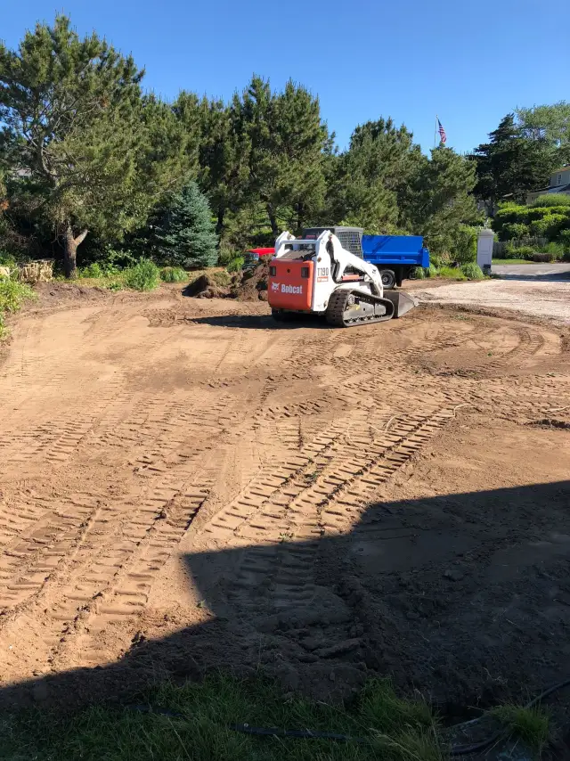 Skid steer grading a driveway area